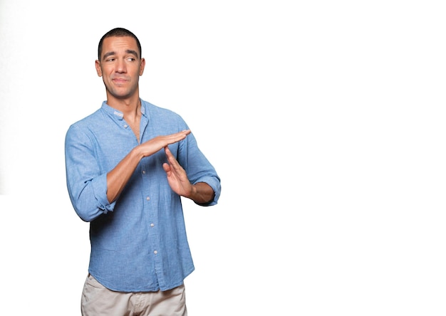 Stressed young man making a time out gesture with his hands