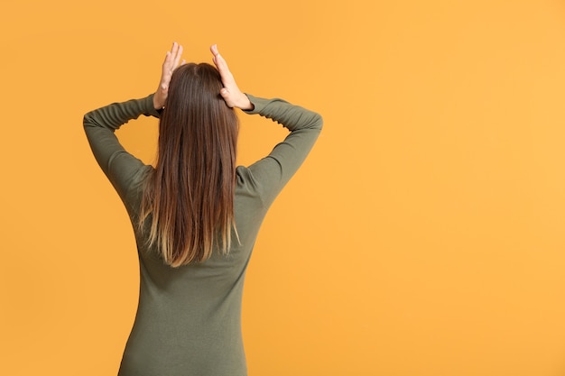 Photo stressed young woman on color background, back view. concept of choice