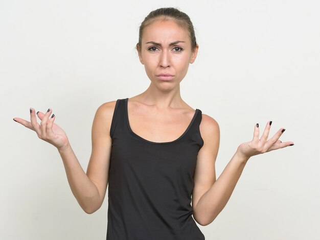 Stressed young woman with brown hair shrugging shoulders