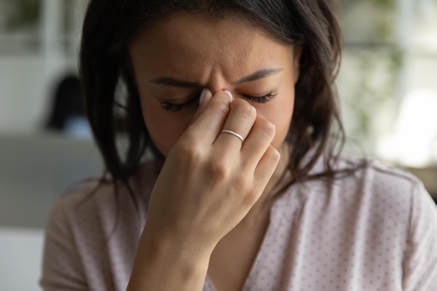 Stressful african american businesswoman holding nose bridge\
suffering from dry eyes syndrome after long laptop use exhausted\
employee executive manager ceo feeling eye strain close up\
view