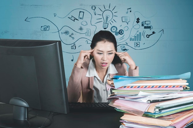 Stressful businesswoman looks at a pile of documents