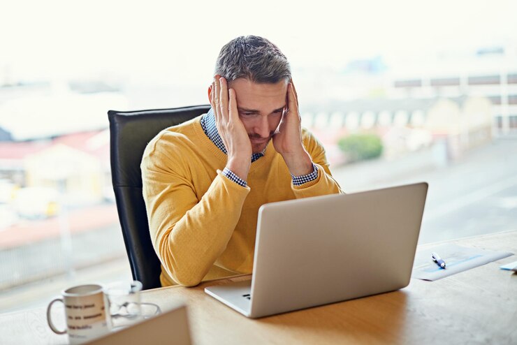 Photo stressful day at the office shot of a businessman working on his laptop at his desk