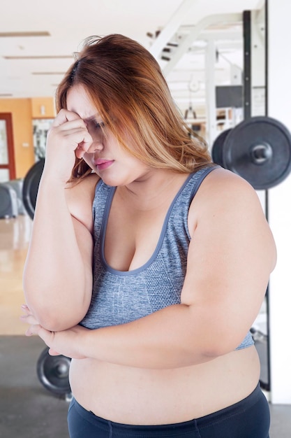 Photo stressful fat woman standing in the gym center