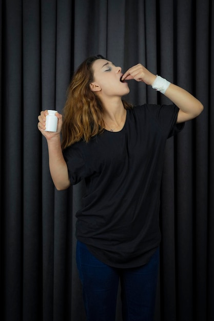 Stressful girl taking pills and stand on black background. High quality photo