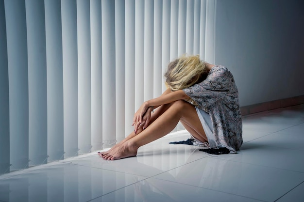 Stressful woman sitting on the floor near window