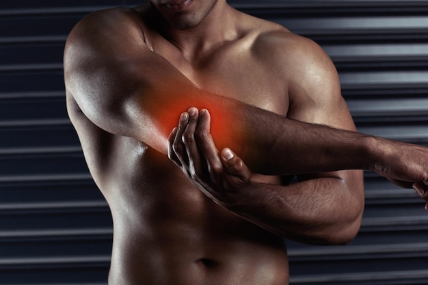 Photo stretch it out shot of an unrecognizable young man holding his elbow in pain during a workout