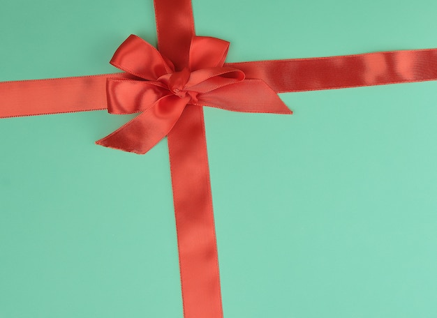 Stretched red silk ribbon and tied bow, green background