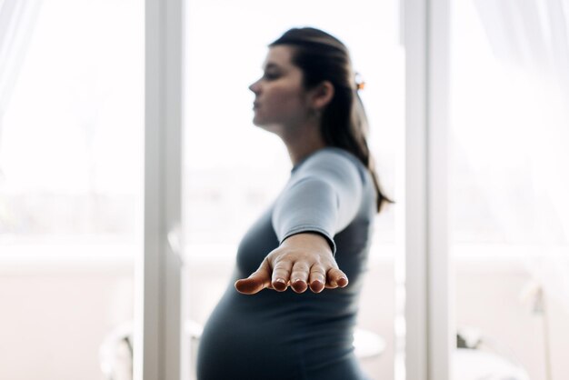 Stretches voor zwangere vrouwen Zwangerschap Stretches om rug- en hoofdpijn te verlichten Zwangere vrouw die stretches thuis doet