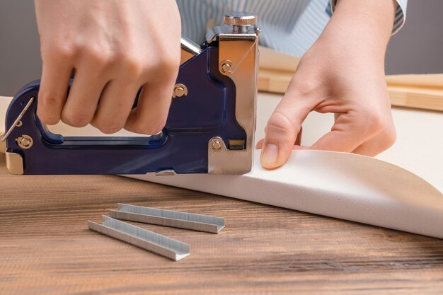 Foto allungando la tela su una barella nello studio dell'artista. le mani delle donne con una graffatrice fissano la tela a una cornice di legno.