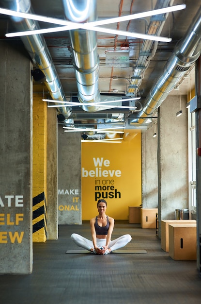 Stretching exercises vertical shot of a young fitness woman in sportswear sitting on yoga mat