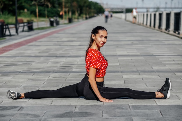 Stretching gymnast woman doing split twine in city