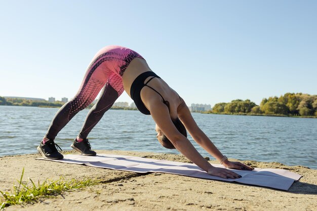 Stretching outside A young woman on a mat in the park trains