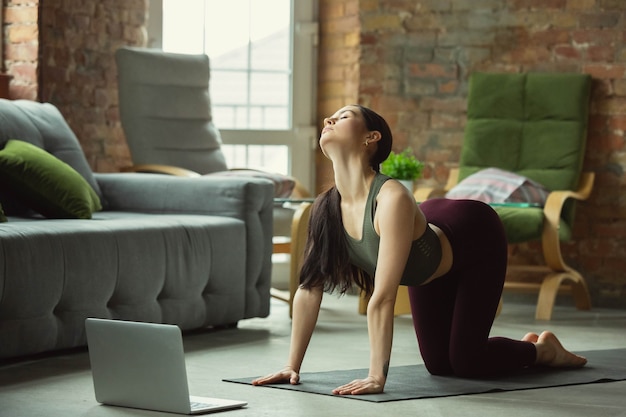 Stretching. Sporty beautiful young woman practicing yoga's asanas like professional at home.