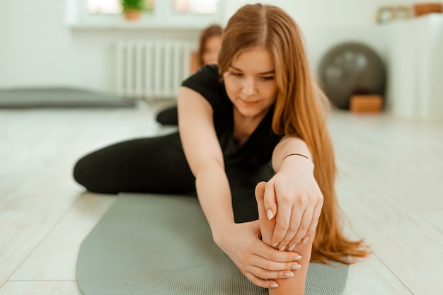 Stretching workout. Healthy lifestyle. Young beautiful girl in black uniform is doing stretching exercise. Akroyoga, yoga, fitness, workout, sport.