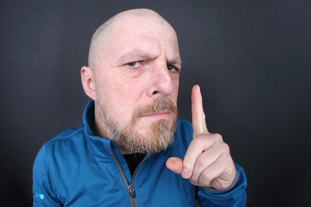 Foto rigoroso uomo barbuto con un dito puntato su uno spazio grigio