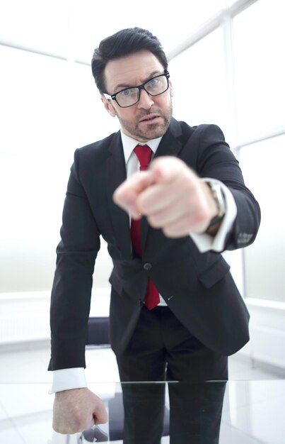 Strict businessman pointing finger at you while standing in his officebusiness concept