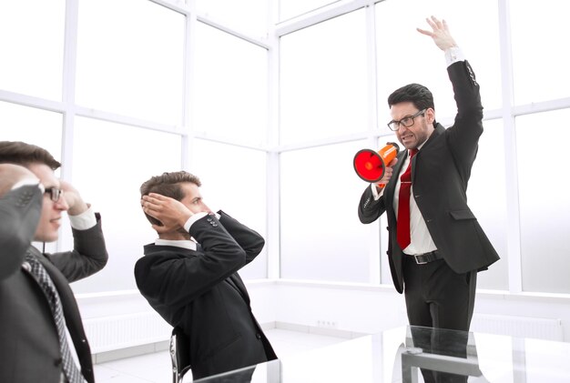 Strict businessman with a megaphone in the conference room photo with copy space