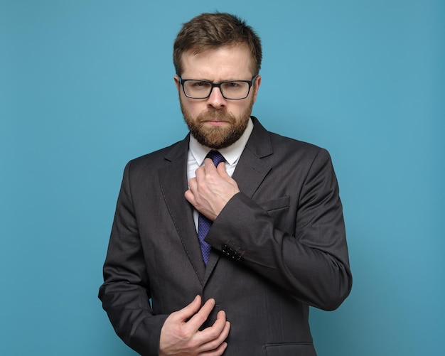 Strict confident business man straightens his tie and with piercing eyes