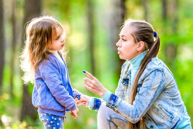 Strict mother talking to her daughter Walk in the summer forest