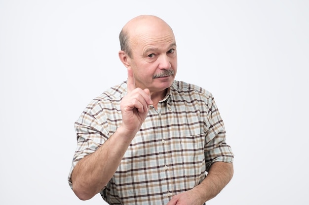 Strict senior man showing index fingers up giving advice