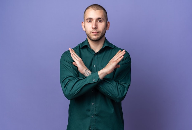 Strict young handsome guy wearing green shirt showing gesture of no 