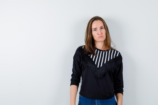 Strict young woman standing on white background