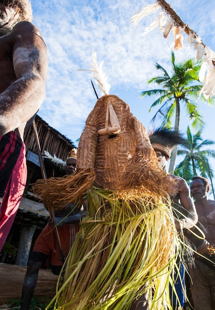 Strijder van de stam Asmat in het kostuum van een boze geest danst een rituele dans.