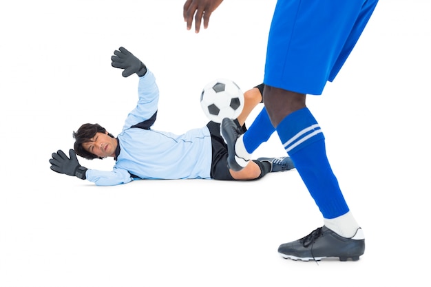 Striker hitting football at goalkeeper