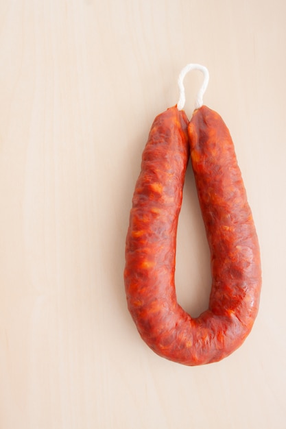 string of chorizo on light wooden background