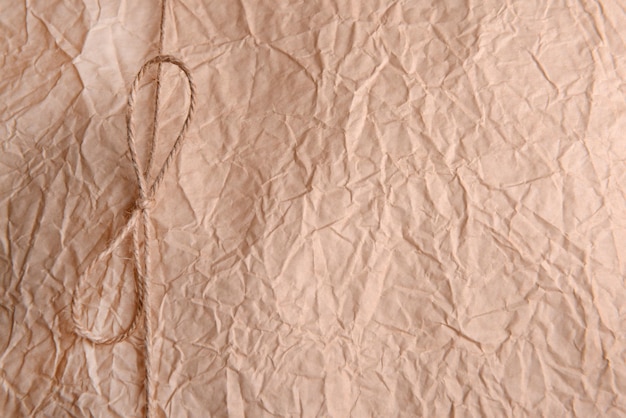 String tied in bow on beige paper packaging closeup