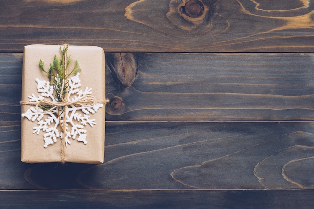 String or twine tied in a bow on kraft paper. Above gift box on wood with space.