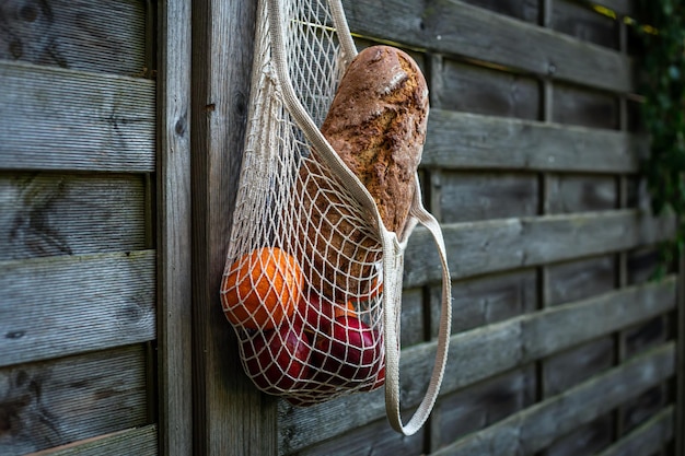 Stringtas met brood en fruit op een houten ondergrond