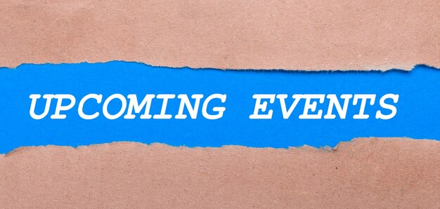 A strip of blue paper with the inscription UPCOMING EVENTS between the brown paper. View from above