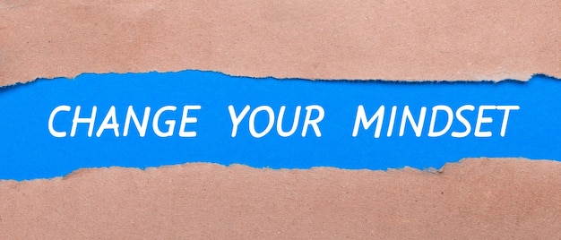 A strip of blue paper with the words CHANGE YOUR MIINDSET between the brown paper. View from above