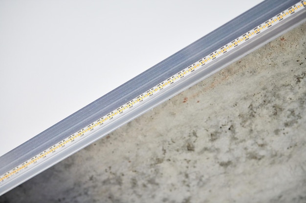 Strip LED lamp met aluminium profiel. Spanplafond met led-verlichting in huis of appartement, binnen, close-up. Huis renovatie concept. Energiebesparende technische achtergrond, moderne constructie