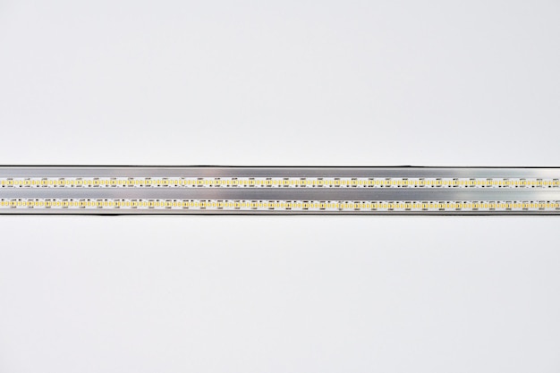 Strip LED light with aluminum profile on white stretch ceiling in house or apartment, indoor close up. Home renovation concept. Modern construction, energy saving technology background