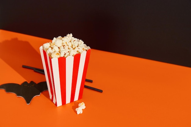 Striped box with popcorn bat napkin and straws on an orange black background