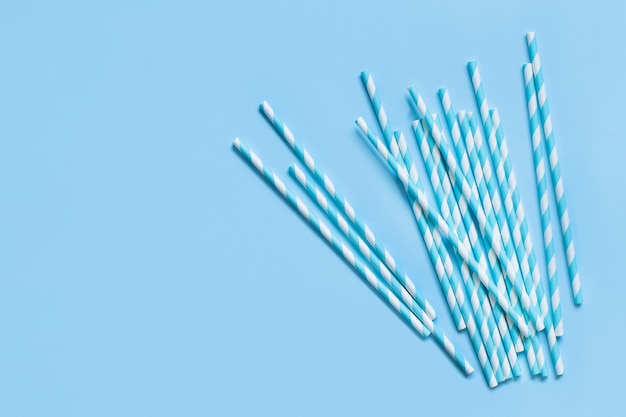 Photo striped and dotted paper drinking straws on light blue background top view