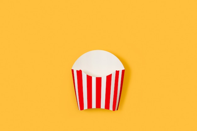 Striped red and white box for fried potatoes on a yellow background