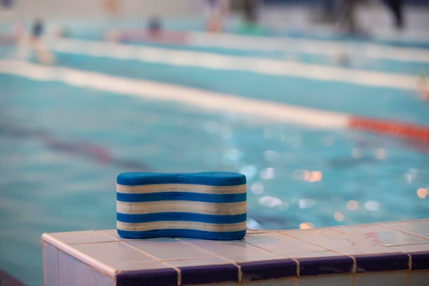 The striped swim training tool rests on the side of the\
pool