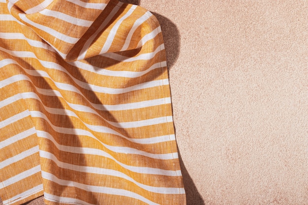 Striped textile yellow serving napkin on beige plastered backdrop