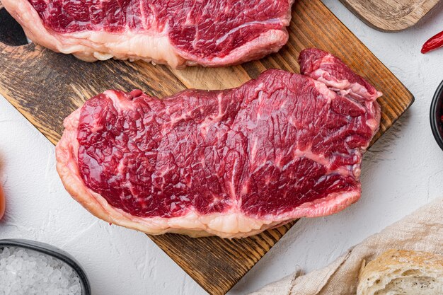 Striploin steak, rauw rundvlees slagerij gesneden, op witte tafel, bovenaanzicht,