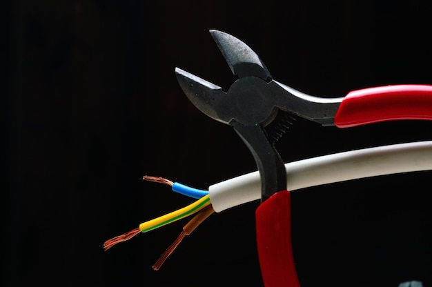 stripped, three-core wire and wire cutters on a dark background. dark background close-up.