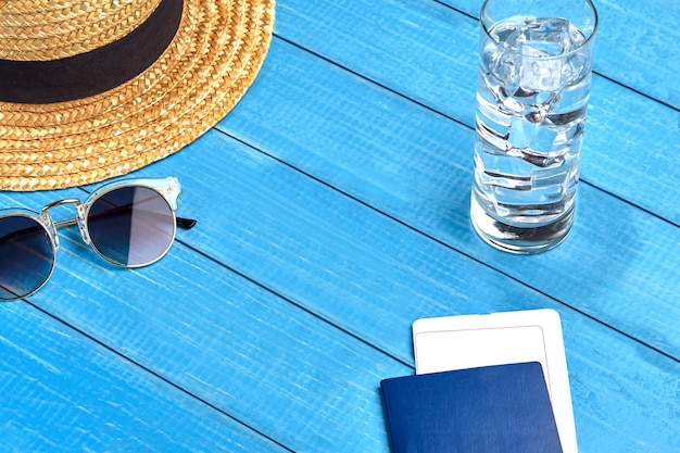 Strohoed, zonnebril, glas water met ijsblokjes en paspoort met kaartje