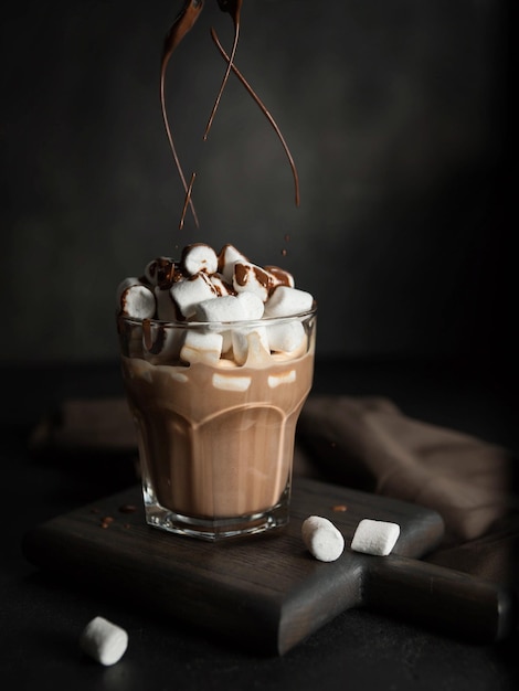 Stromende chocolade in een kop warme chocolademelk met marshmallow op een zwarte achtergrond