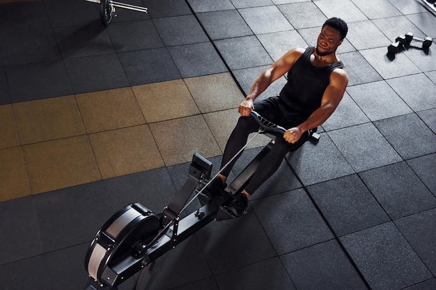 Strong african american man in sportive clothes have workout day in the gym and using equipment Conception of power and strength