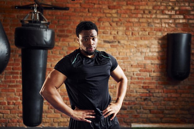 체육관에 서 있는 낚시를 좋아하는 옷을 입은 강한 아프리카계 미국인 남자