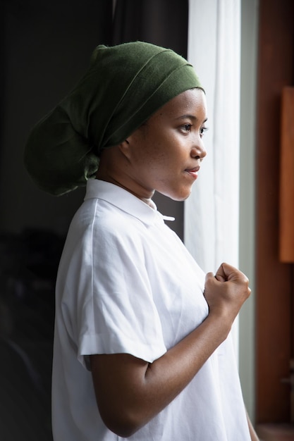 Strong African black woman cancer patient recovering from sickness wearing head scarf to cover hair loss and pain concept of cancer awareness