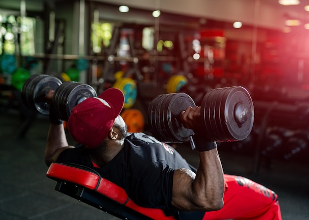 Strong african man in a gym Handsome man with big muscles feeling confident while training hard at the dark gym Stock photo