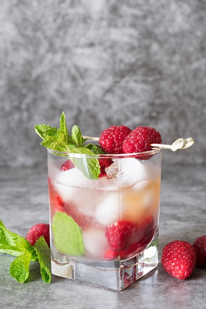 Photo strong alcoholic beverage with raspberry in a square glass